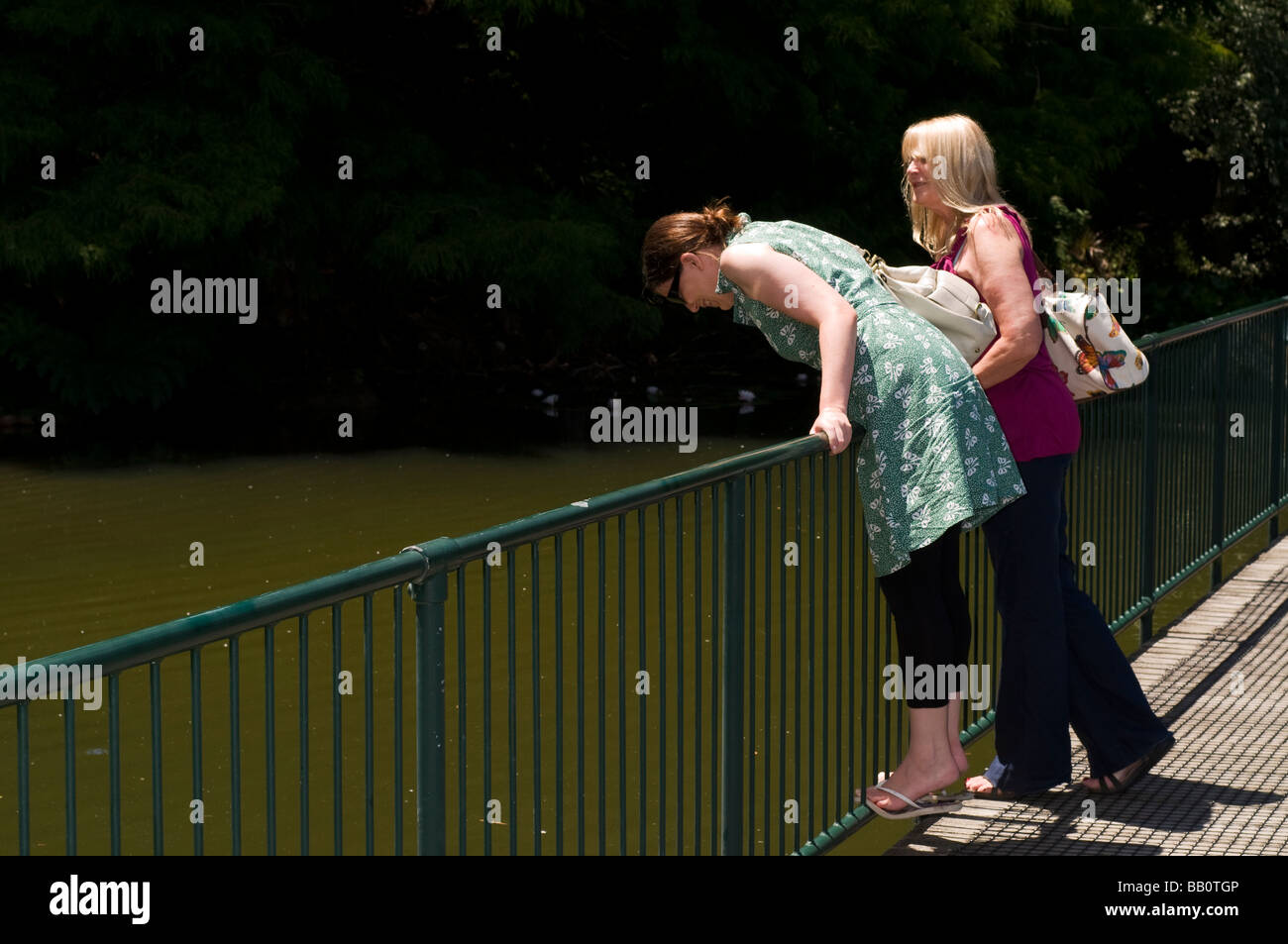 Mother and daughter standing on walkway over pond, Hamilton gardens