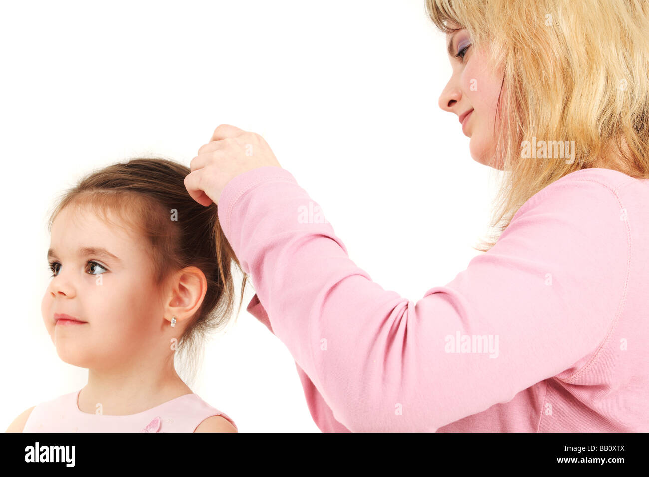 Portrait of mother helping daughter with hair, studio shot Stock Photo