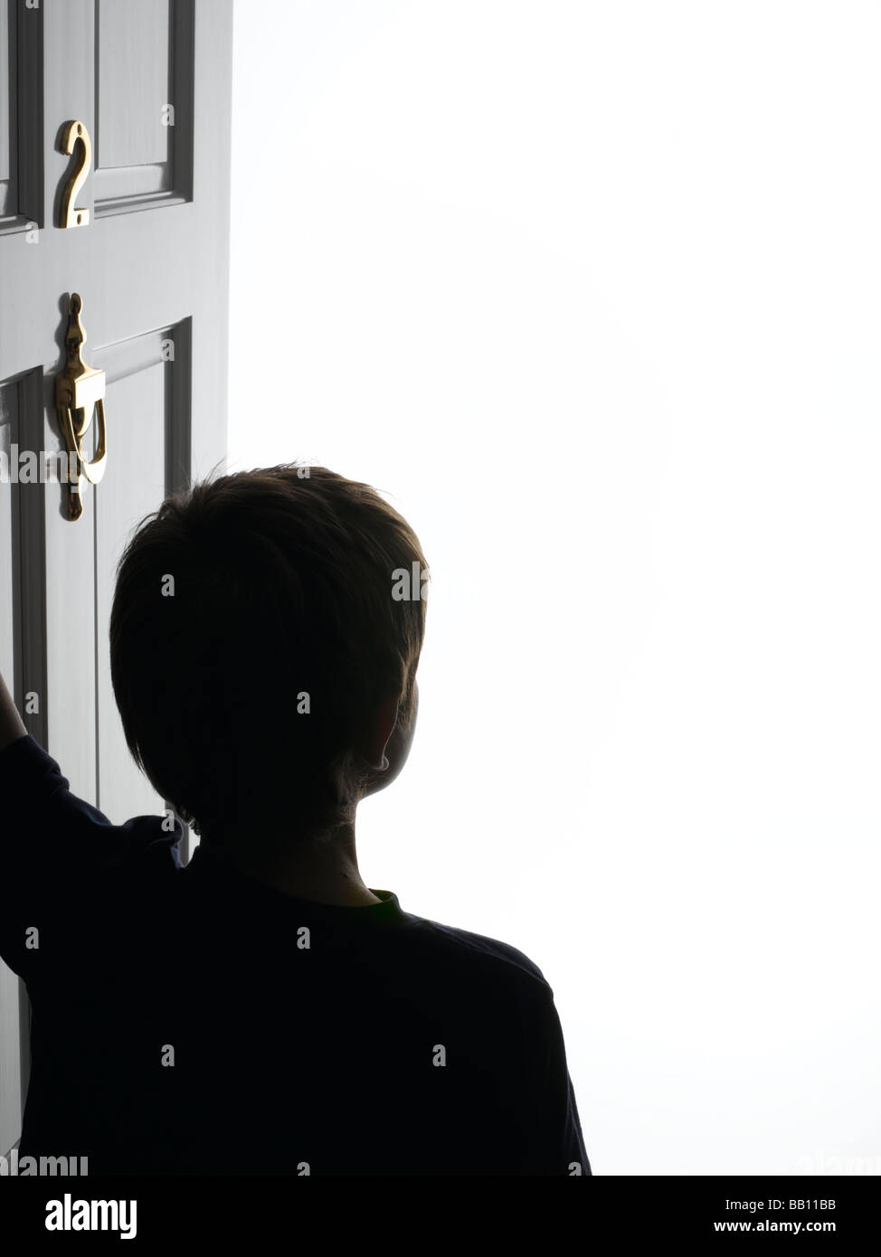 Young boy opening the front door Stock Photo