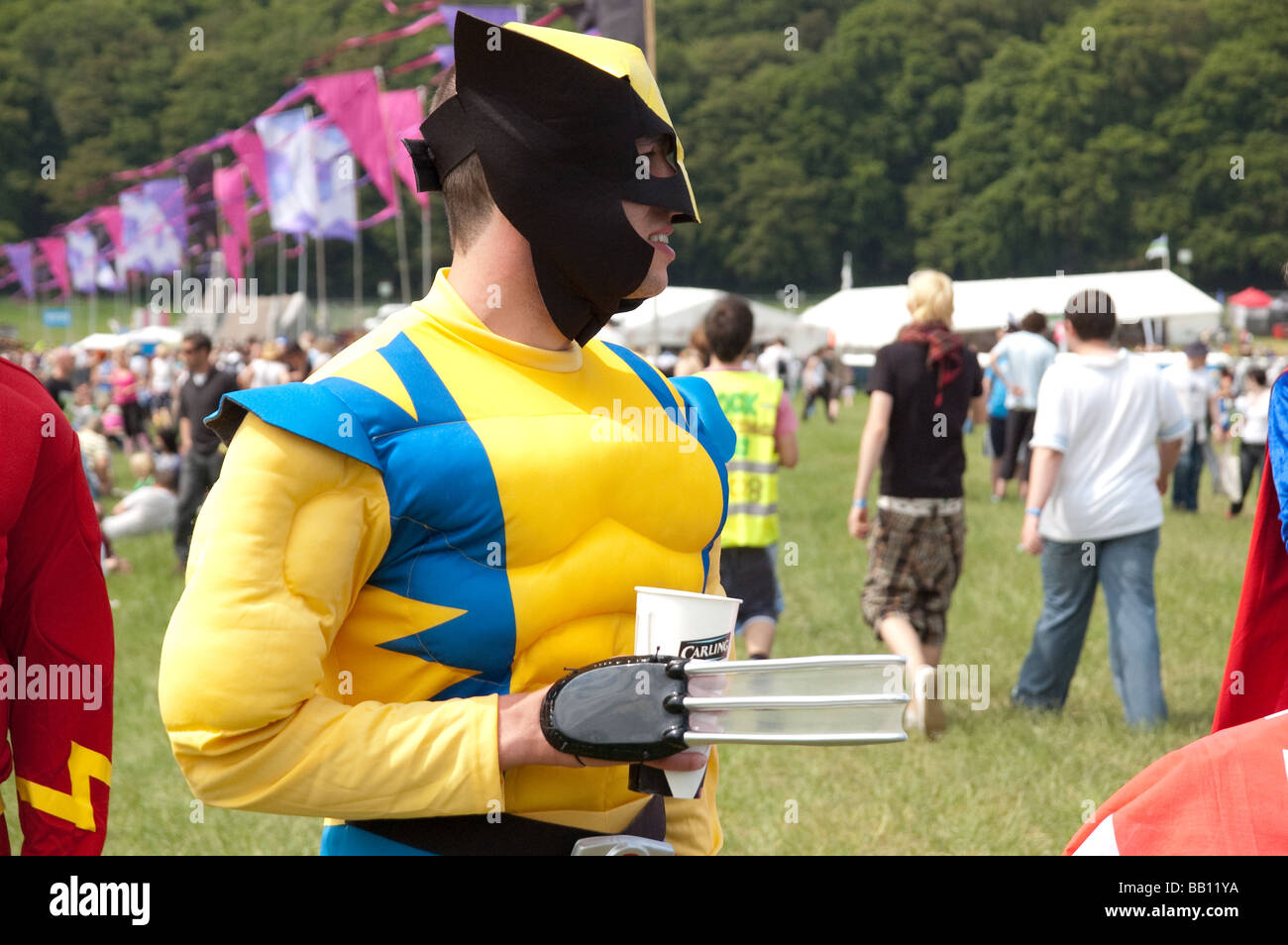 A festival goer dressed as Wolverine from the X-Men drinks from a paper cup at a music festival Stock Photo