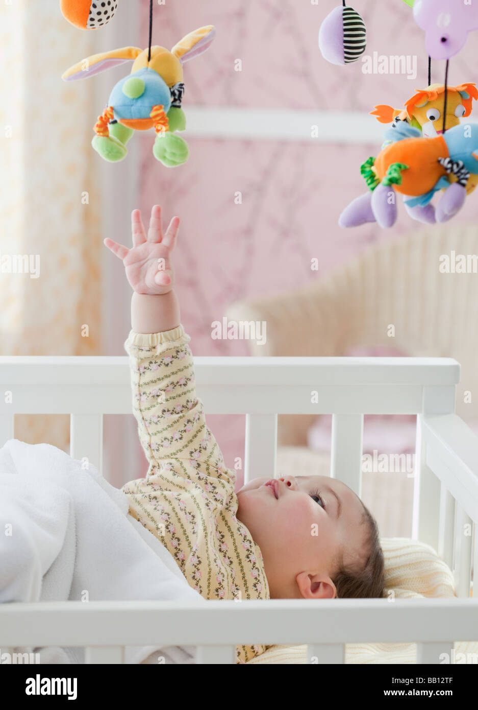 Mixed race baby girl reaching for toy mobile Stock Photo