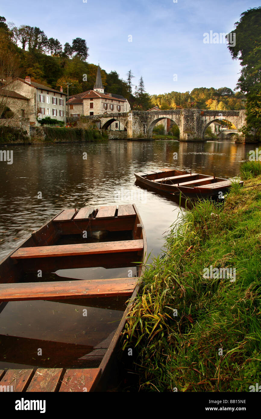 A view of the old medieval bridge at St Leonard de Noblat with two old rowing boats in the foreground. Limousin France. Stock Photo