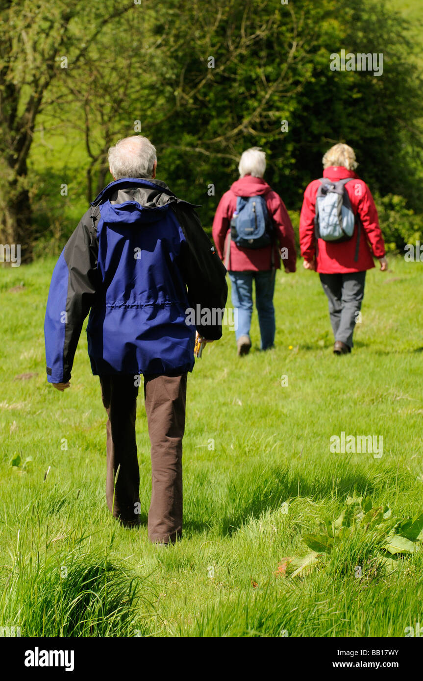 Female hikers walking in the countryside being followed by a man Stock Photo