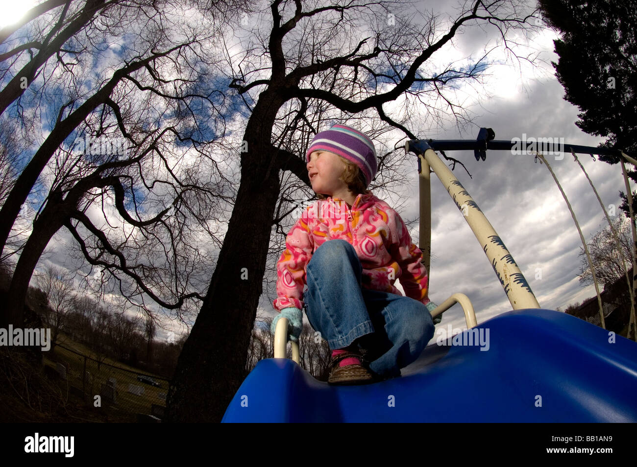 A young girl gets ready to go down a slide during a cool crisp day