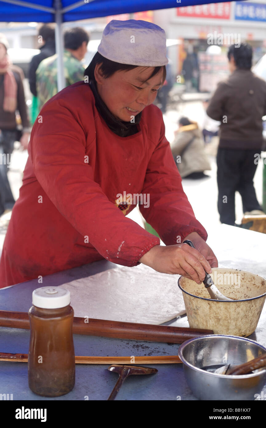 A woman rolling dough on a street market stall in Beijing China Stock