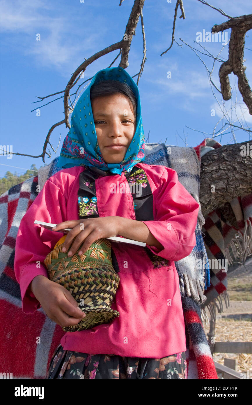 Girl dressed in traditional clothing holding a basket she made in the Tarahumara village of San Alonso in Copper Canyon Mexico Stock Photo