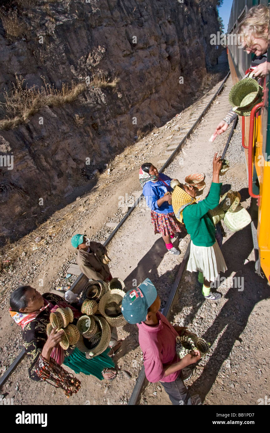 Woman buys baskets from Tarahumara native Indian girls while leaning out of Copper Canyon El Chepe train. Stock Photo
