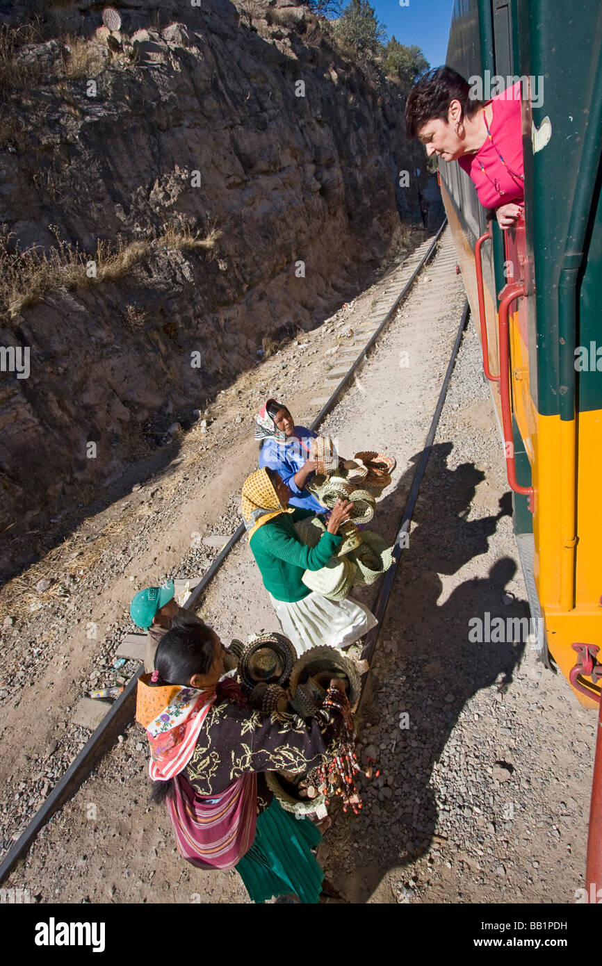 Woman buys baskets from Tarahumara native Indian girls while leaning out of Copper Canyon El Chepe train. Stock Photo