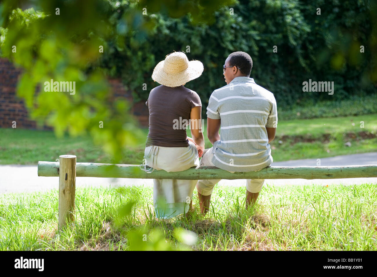 Rear view of a couple sitting on a park fence,  Johannesburg, Gauteng Province, South Africa Stock Photo