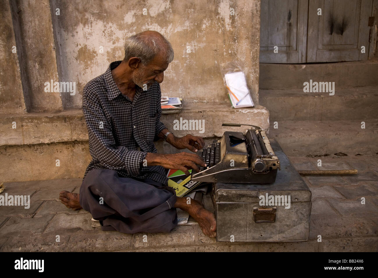 A man sits on the street working on a typrewriter in the heart of the old city of Ahmedabad, Gujarat. Stock Photo