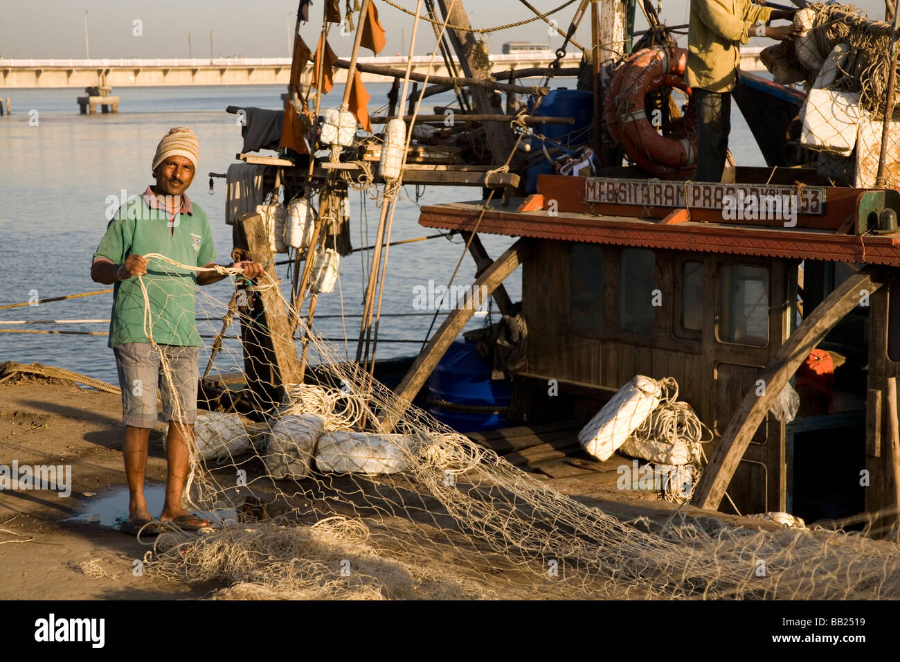 A fishermen checks his nets in the former Portuguese colony of Diu, India. He stands by his boat early in the morning. Stock Photo