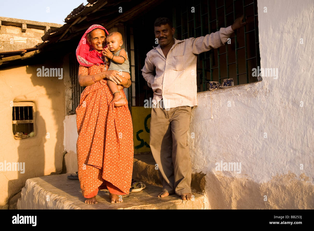 A typical rural house and family in the Gujarati town of Sasan, India. The woman in a red sari