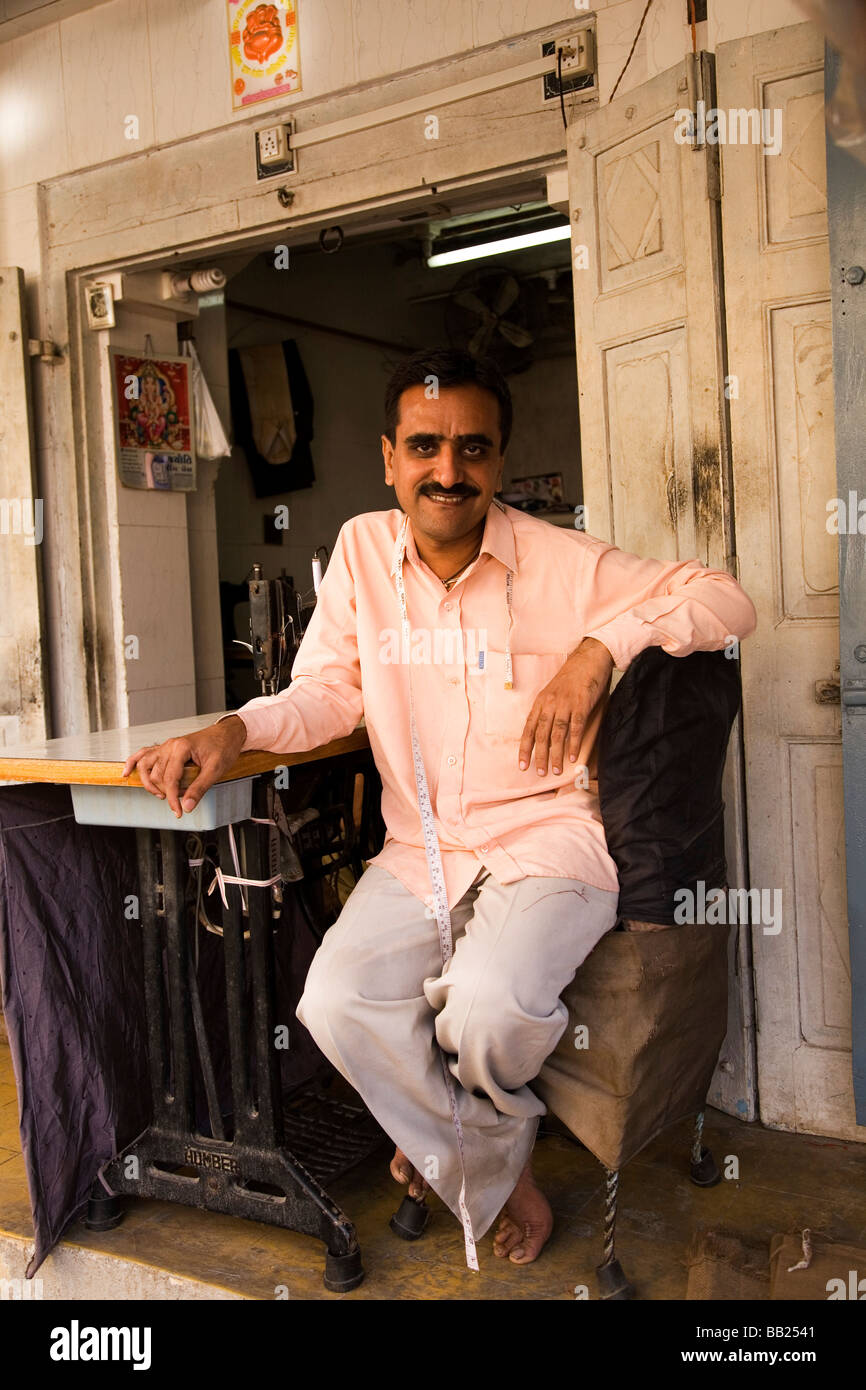 A tailor in the Gujarati city of Rajkot, India. He sits outside on the veranda of his business. Stock Photo