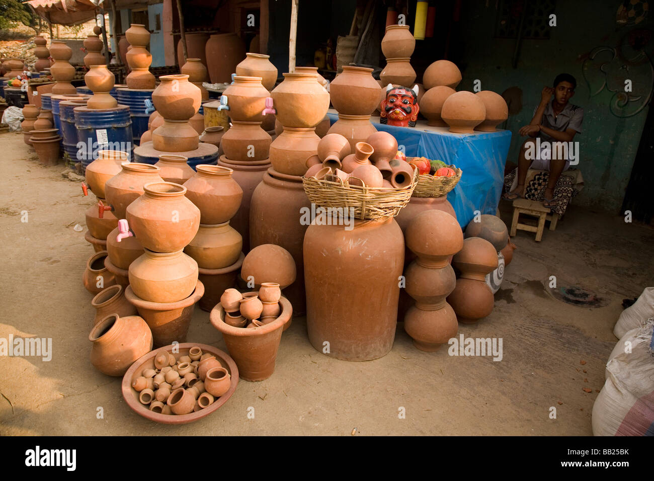A lad sits by a stall selling pottery goods in Bangalore, India. A