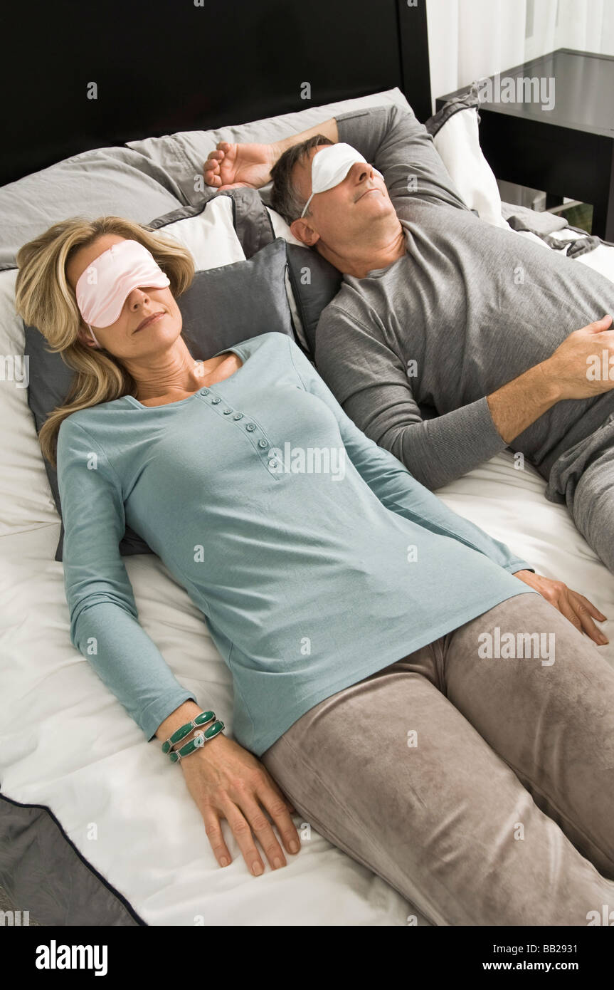 Couple sleeping in bed wearing eye masks Stock Photo Alamy