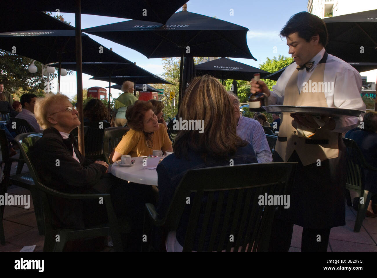 South America; Argentina; Buenos Aires.  A waiter delivers a bottle to people enjoying coffee at an outdoor cafe in Recoleta. Stock Photo