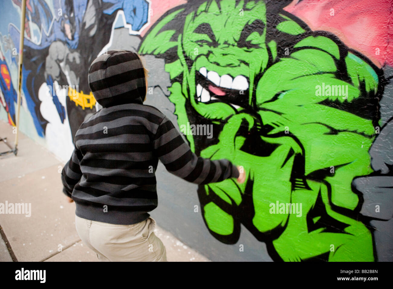 boy running up to a painting of the incredible hulk on a wall Stock Photo