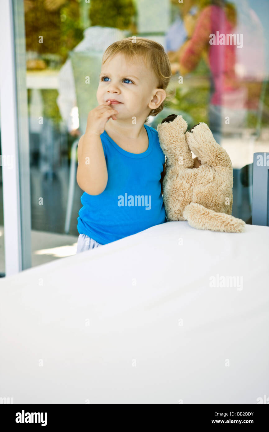 Baby boy holding a teddy bear and looking up Stock Photo - Alamy