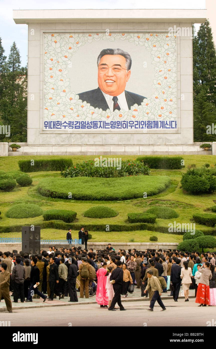 People walk past portrait of Kim Il Sung, Pyongyang, North Korea Stock Photo