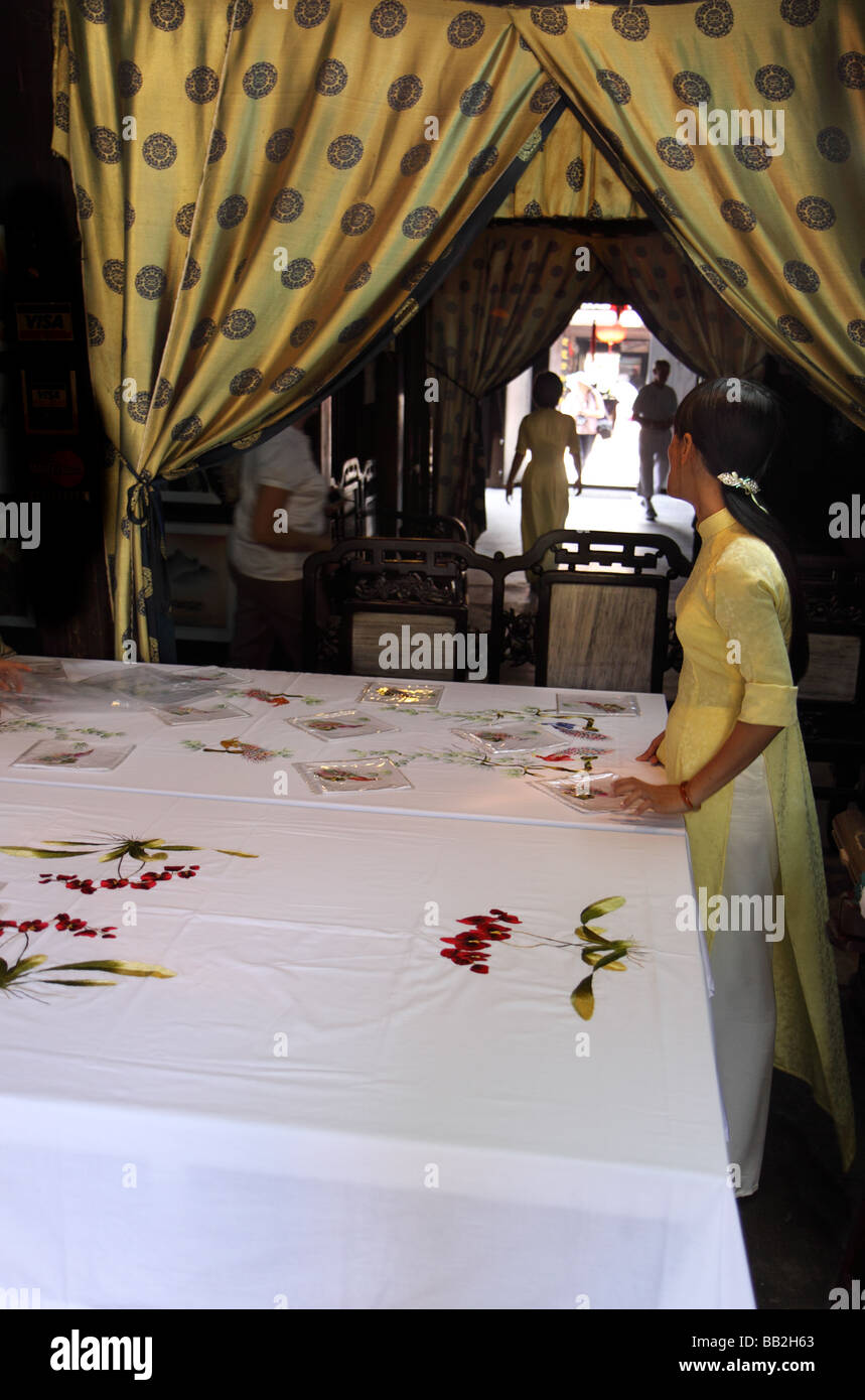 Vietnamese lady showing tourists silk embroidered table cloth and
