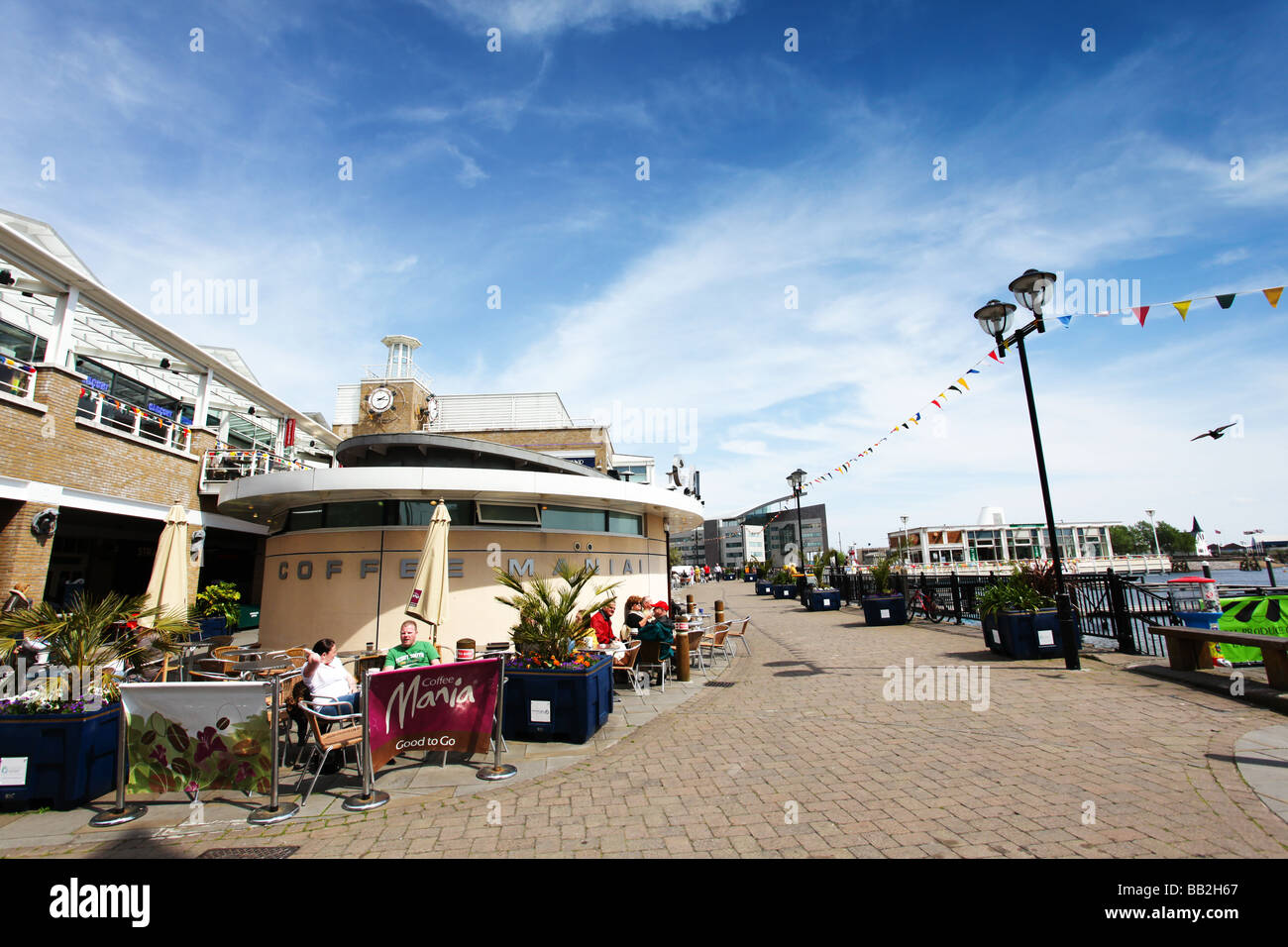 Tourists enjoy eating drinking at outdoor cafes restaurants overlooking Cardiff Bay inner harbour at the waterfront area Wales Stock Photo
