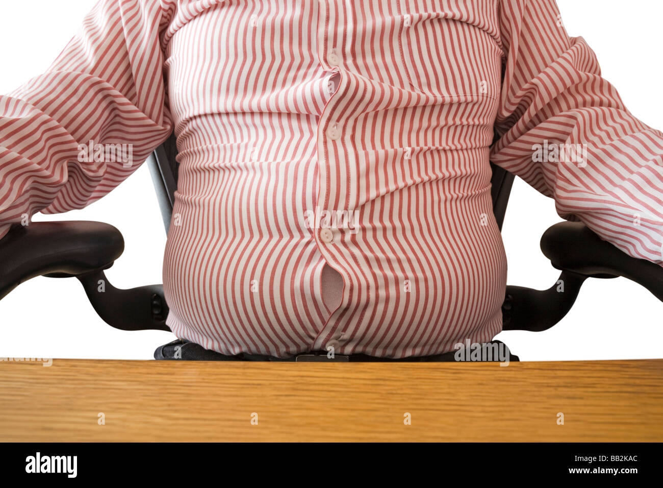 male with bulging stomach sits on a chair at his office desk Stock Photo