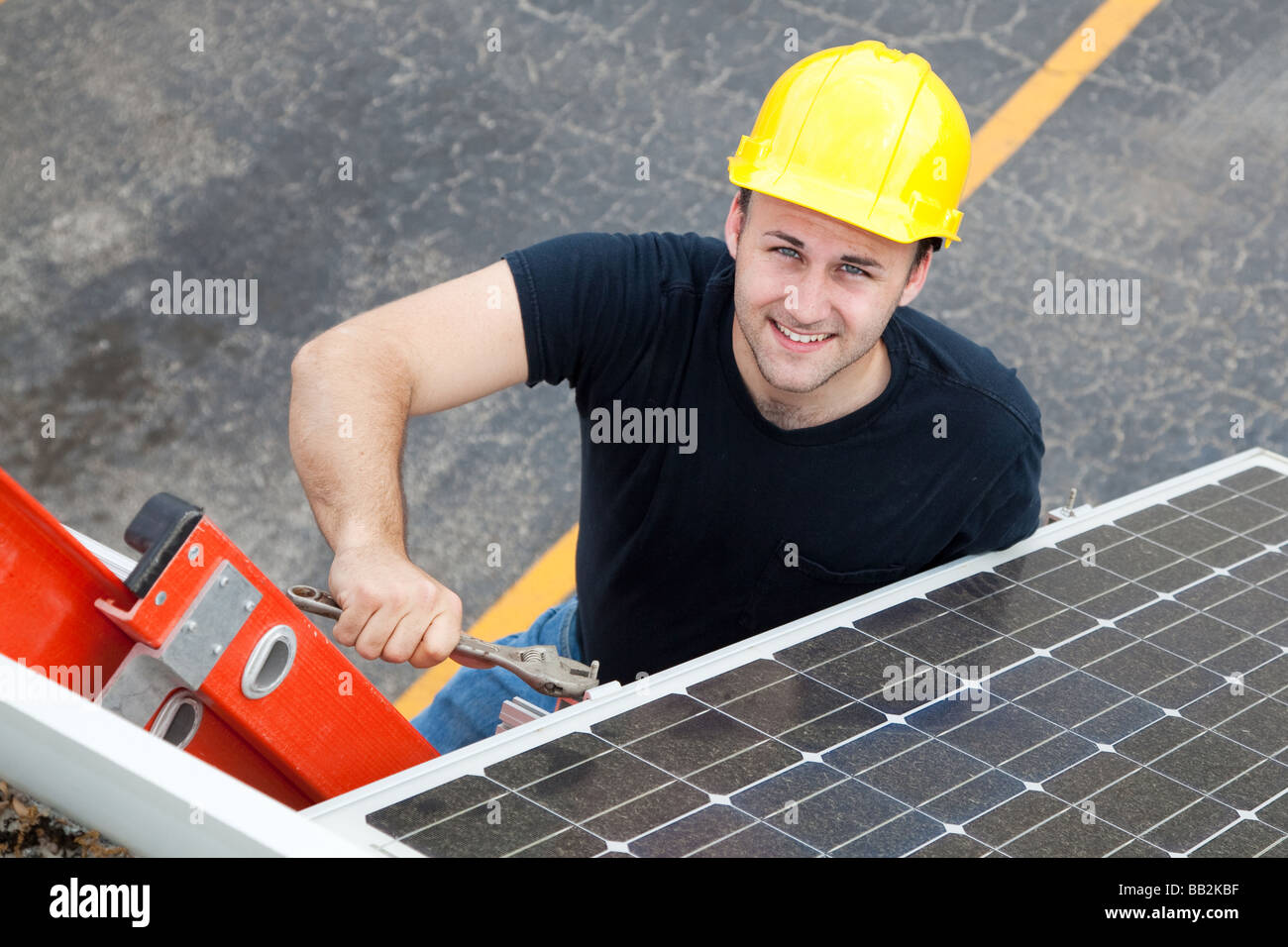 Young electrician on a ladder installing solar panels  Stock Photo