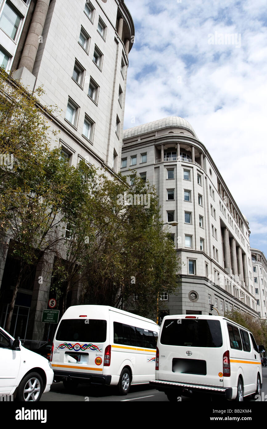 Two white African taxis driving past historic buildings in downtown Johannesburg City Stock Photo