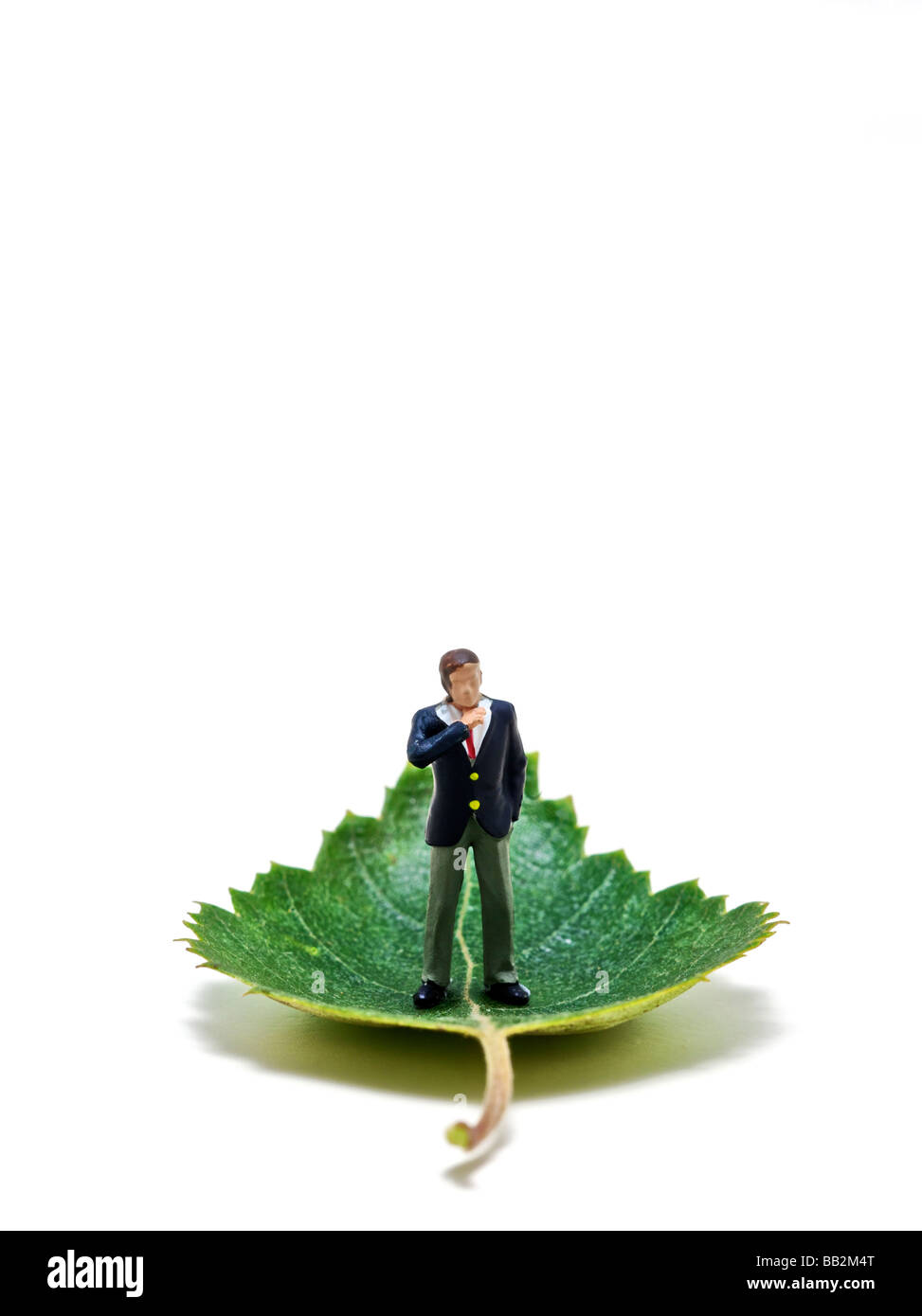 Model business man standing upon a green leaf against a white background in studio Stock Photo