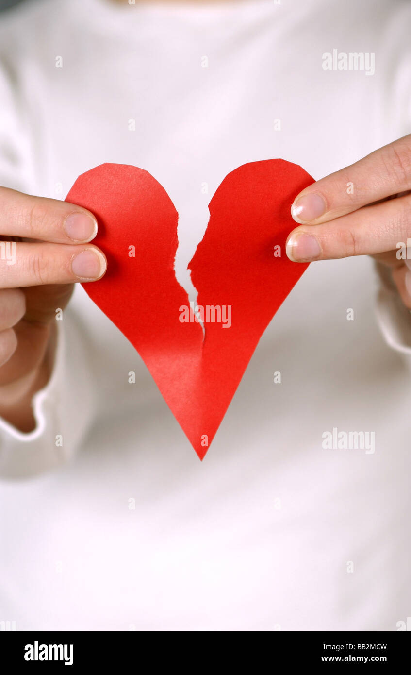 a woman holding a broken heart made of paper Stock Photo - Alamy