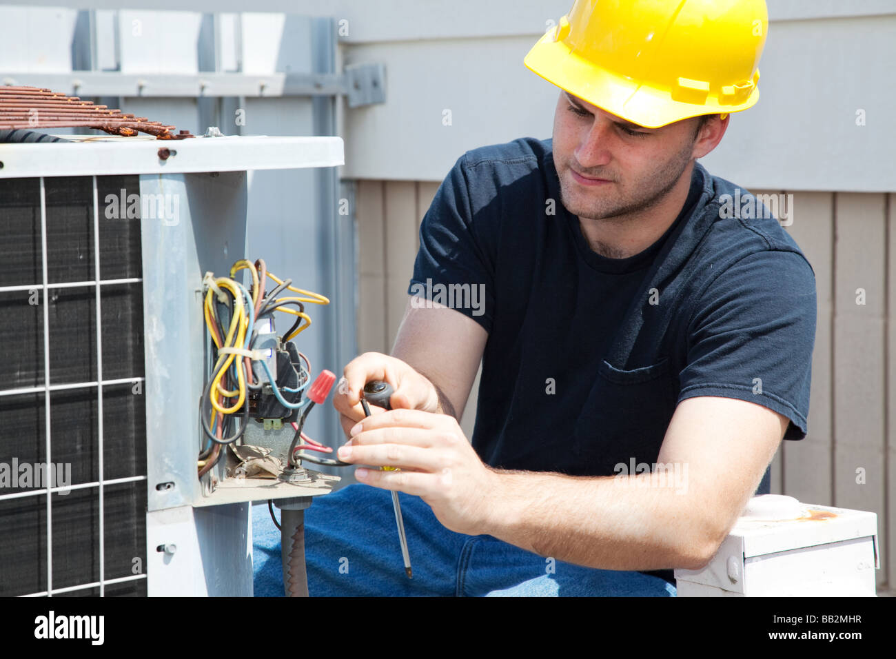 Young repairman fixing an industrial air conditioning compressor Stock