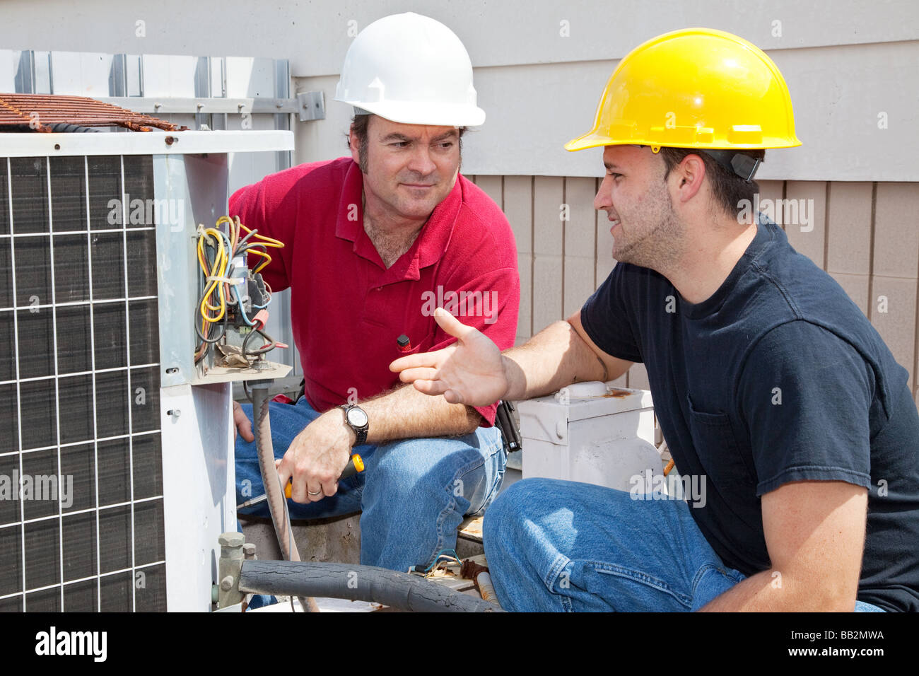 Air conditioning repairmen discussing the problem with a compressor