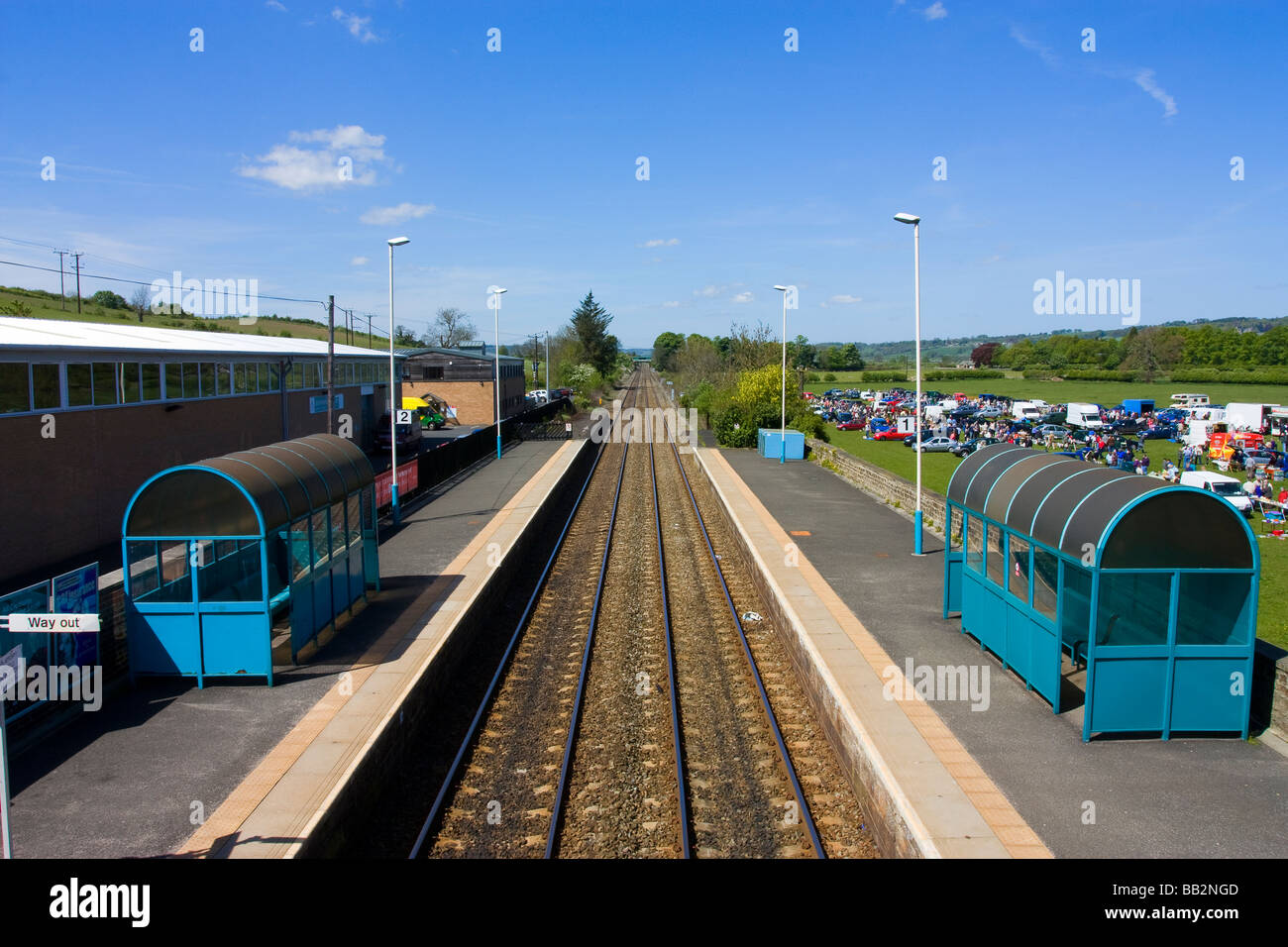 Corbridge railway station with glimpse of car boot fair in field Stock Photo