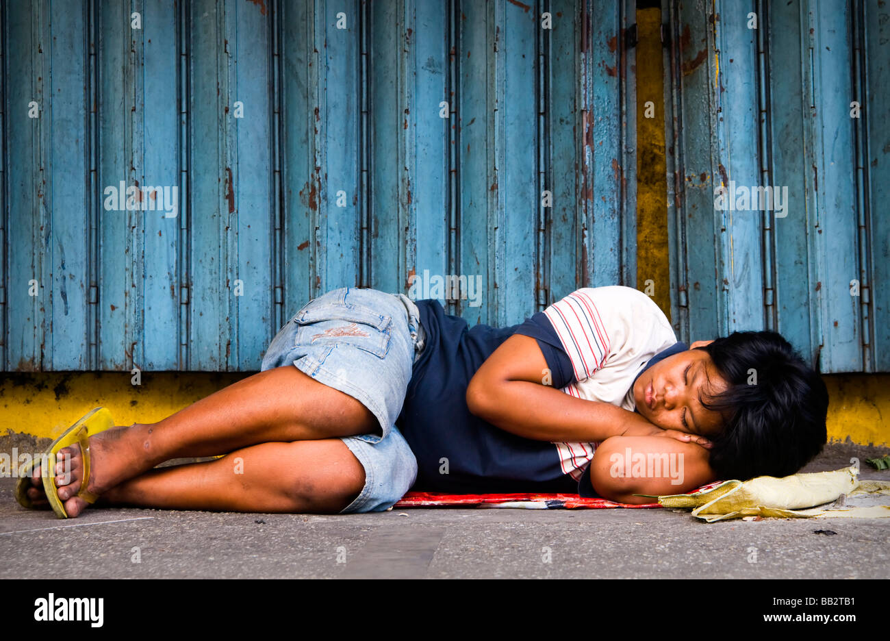 A homeless girl sleeping in the streets of Manila. Stock Photo