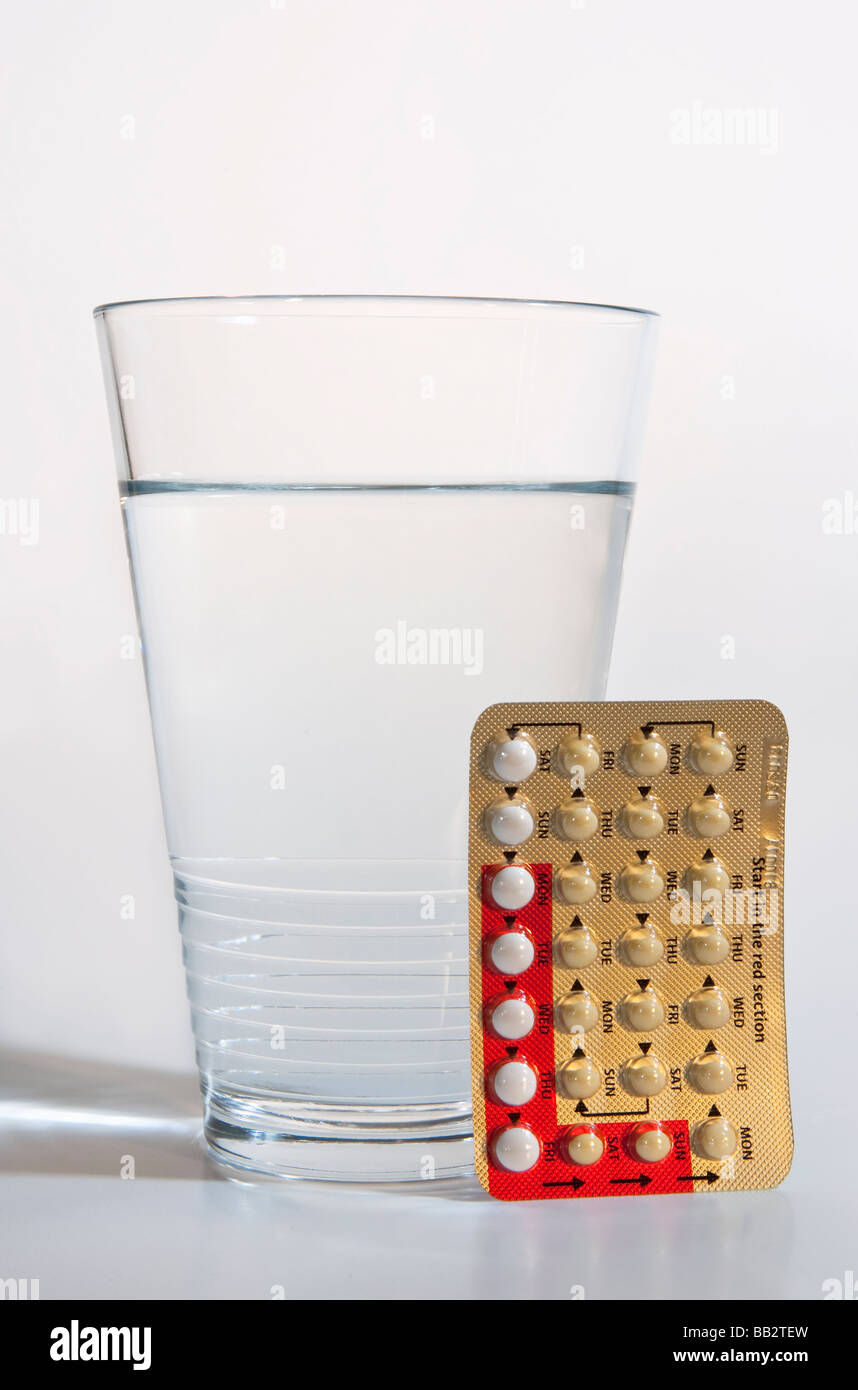 A glass of water and contraceptive pills. Stock Photo