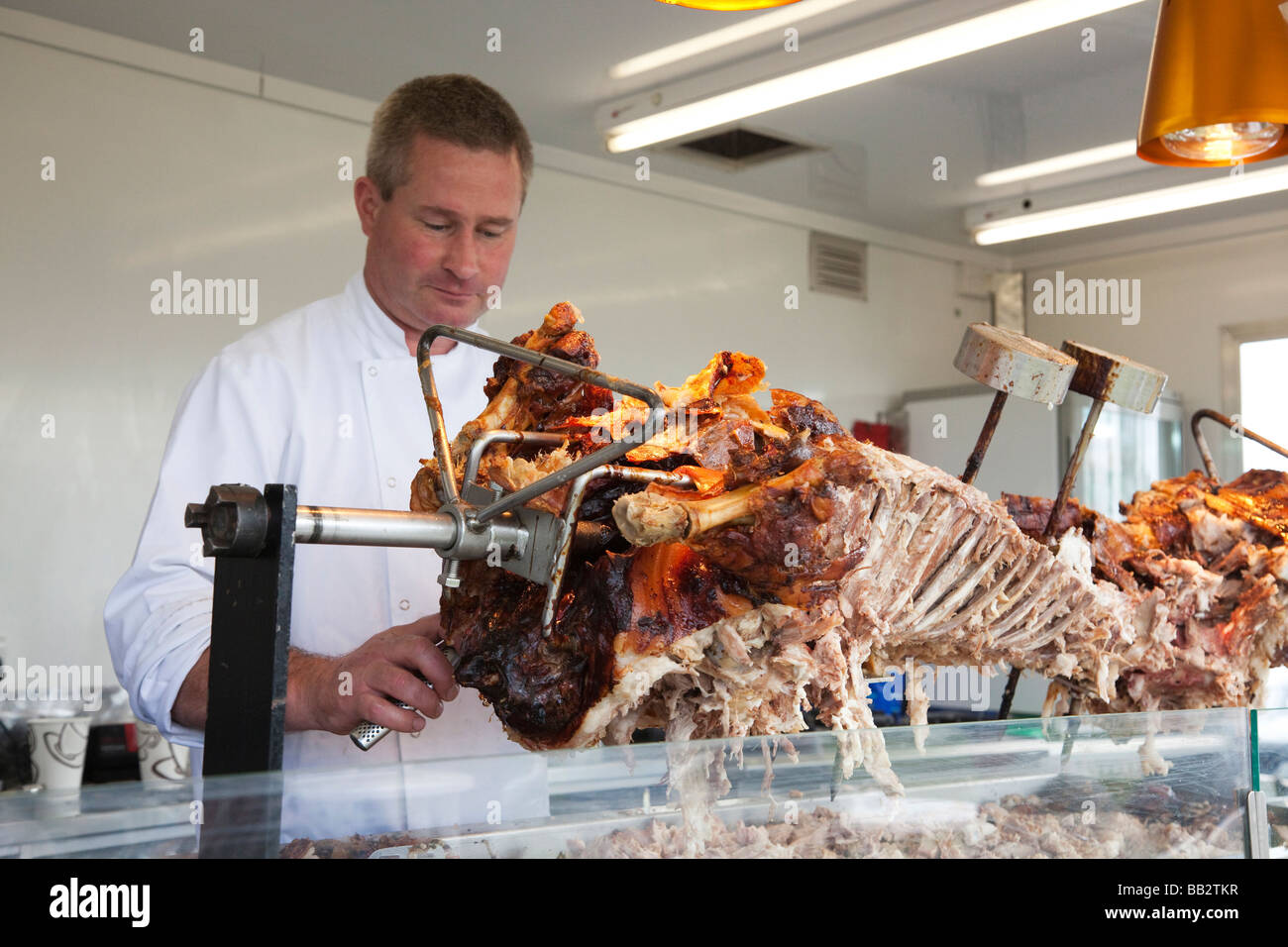 hog roast meat being cooked and served at a food stall Stock Photo