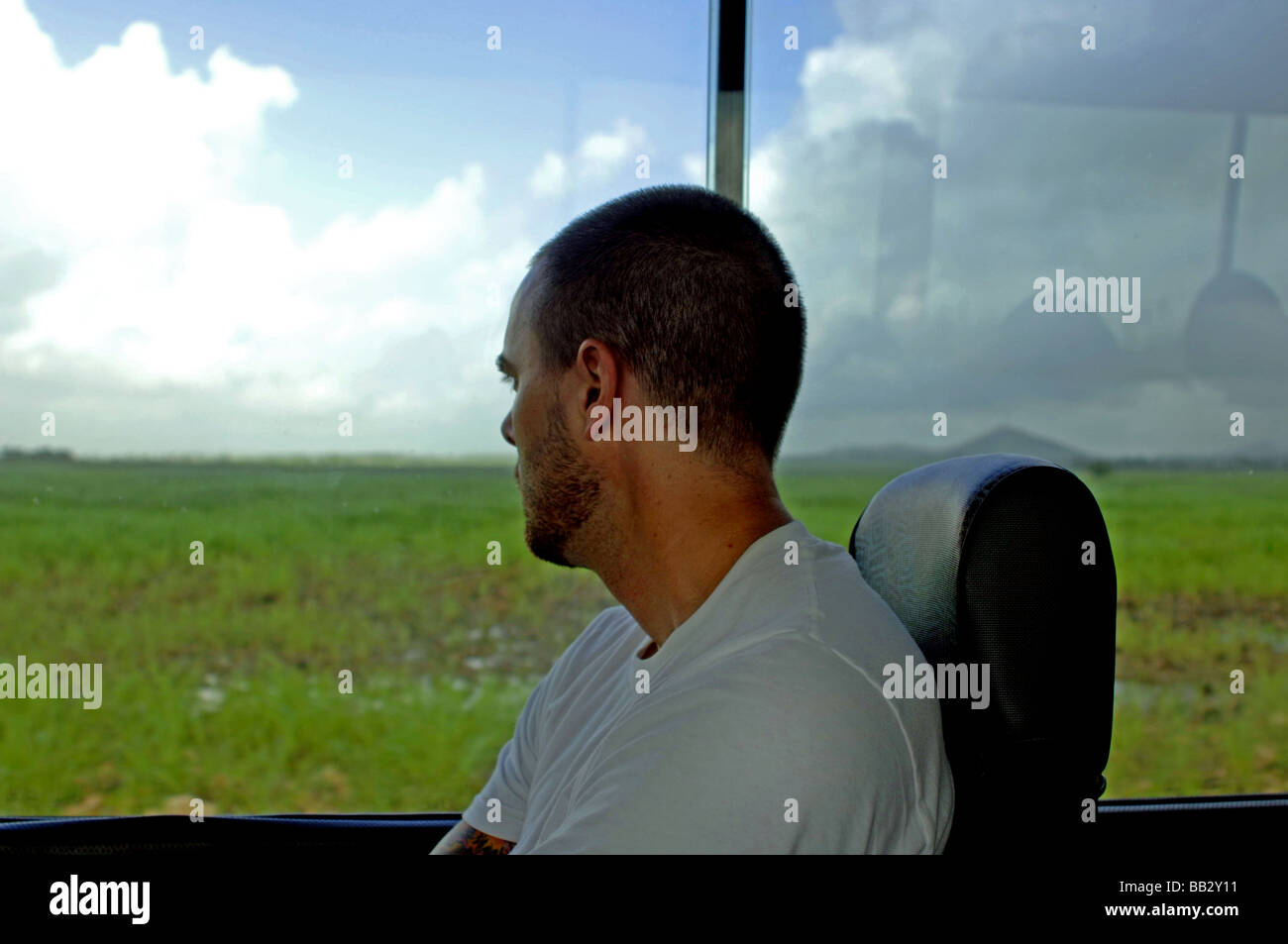 Tourist on a public bus gazes out the window at the green tropical country side while deep in thought Stock Photo