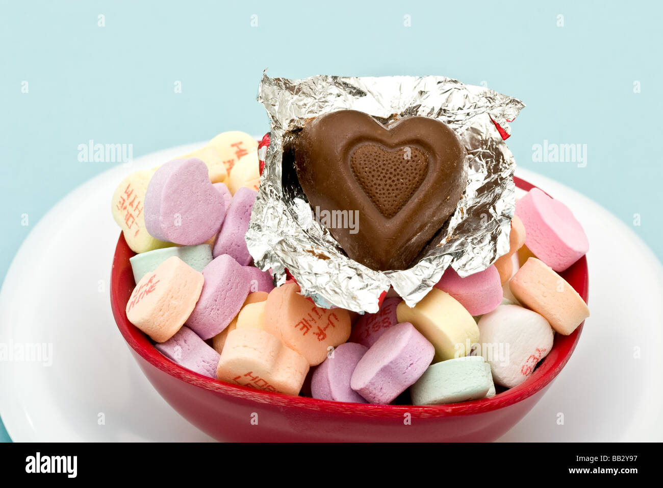 Heart shaped chocolate candy unwrapped atop of heart shaped hard candies Stock Photo