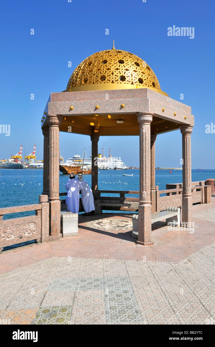 Dhows Muscat moored in Muttrah harbour with Costa cruise ship docked in Port Sultan Qaboos seen beyond promenade and gold dome sun shelter Oman Gulf Stock Photo