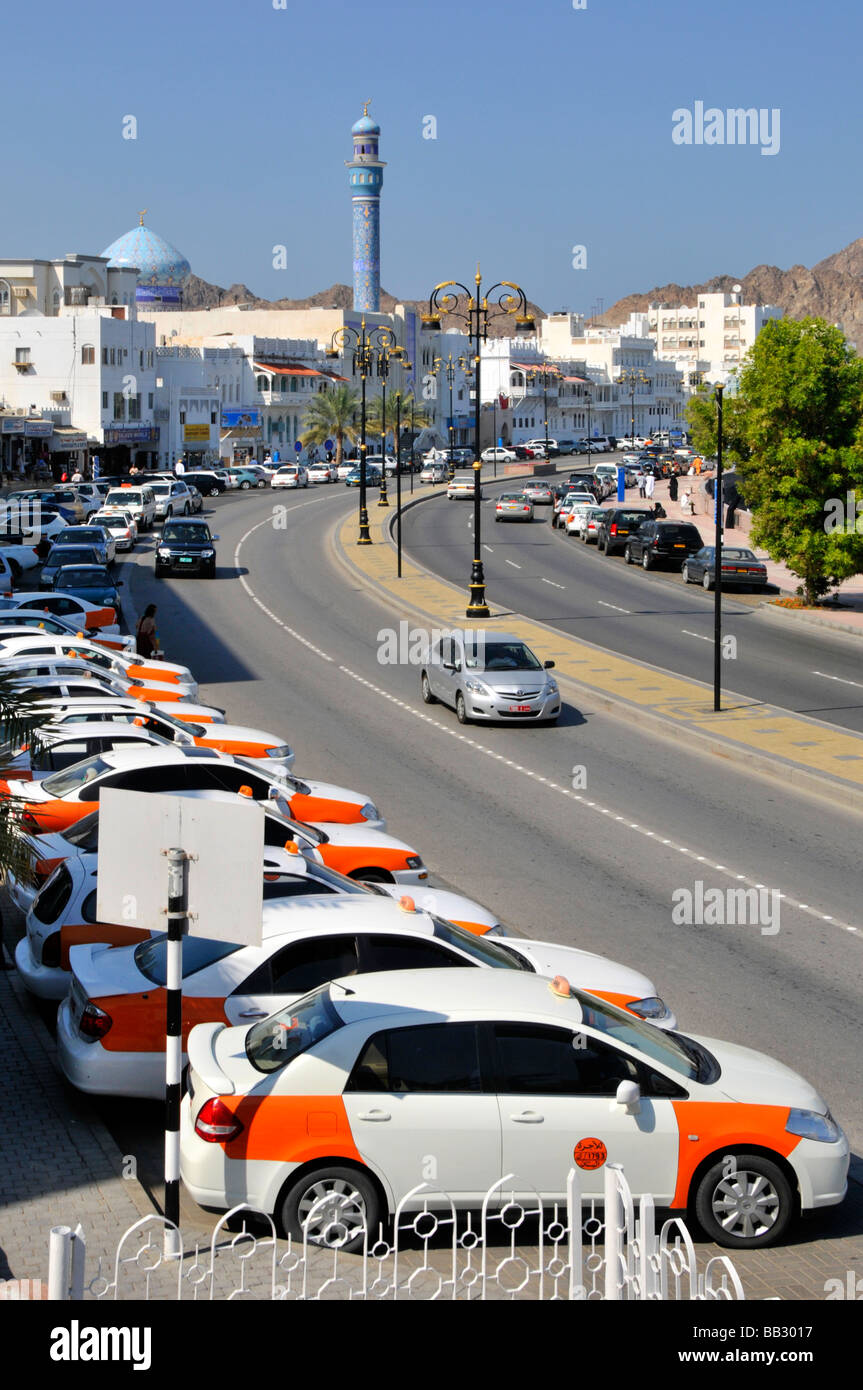 Muttrah Muscat long line of parked taxi cabs beside waterfront dual carriageway with mosque beyond Stock Photo