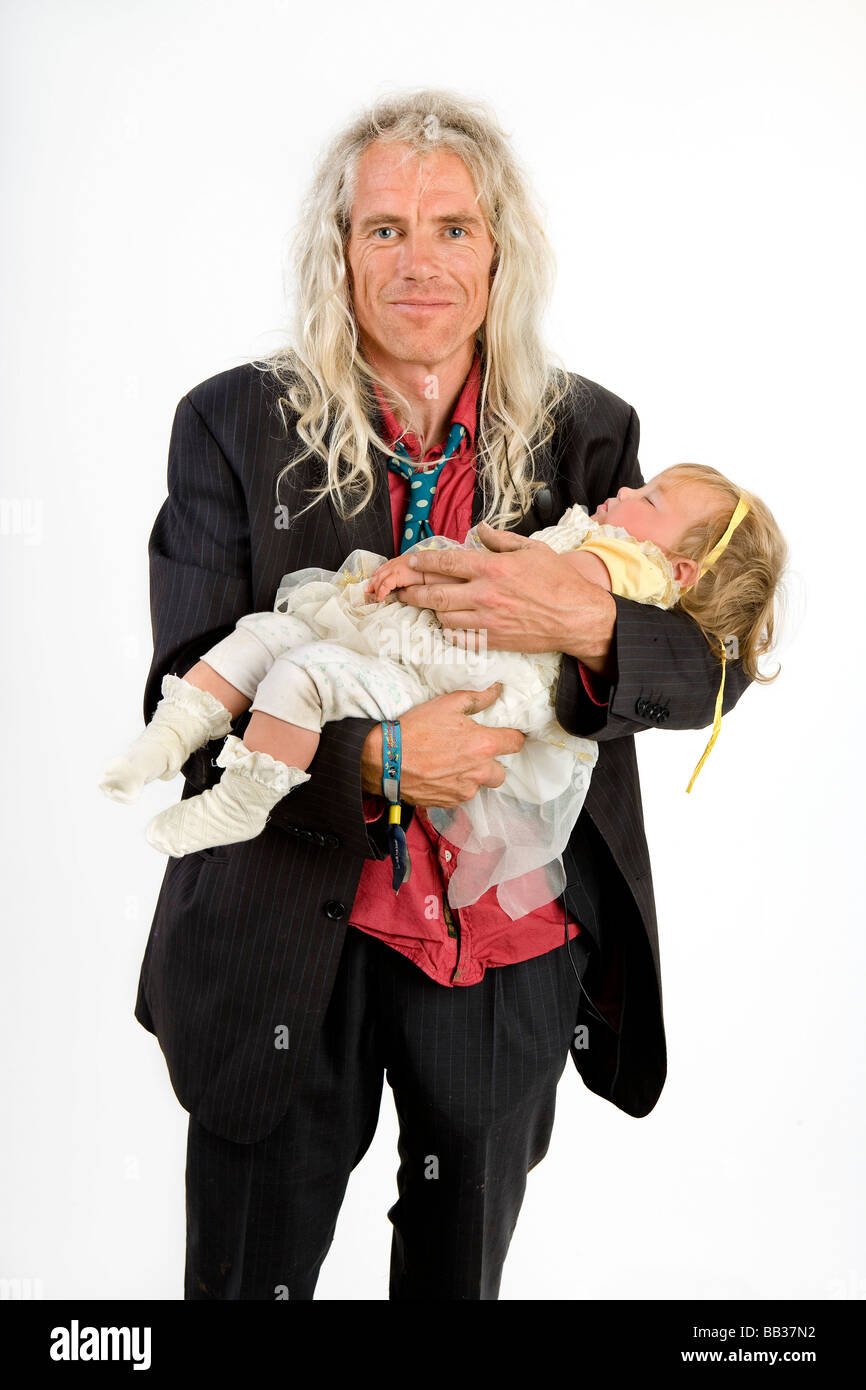 A man poses with a sleeping baby at Glastonbury festival white tent, United Kingdom Stock Photo