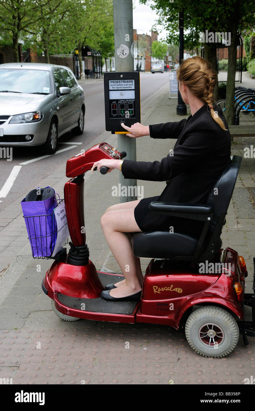 Female mobility scooter driver driving in town centre at traffic control crossing point Stock Photo