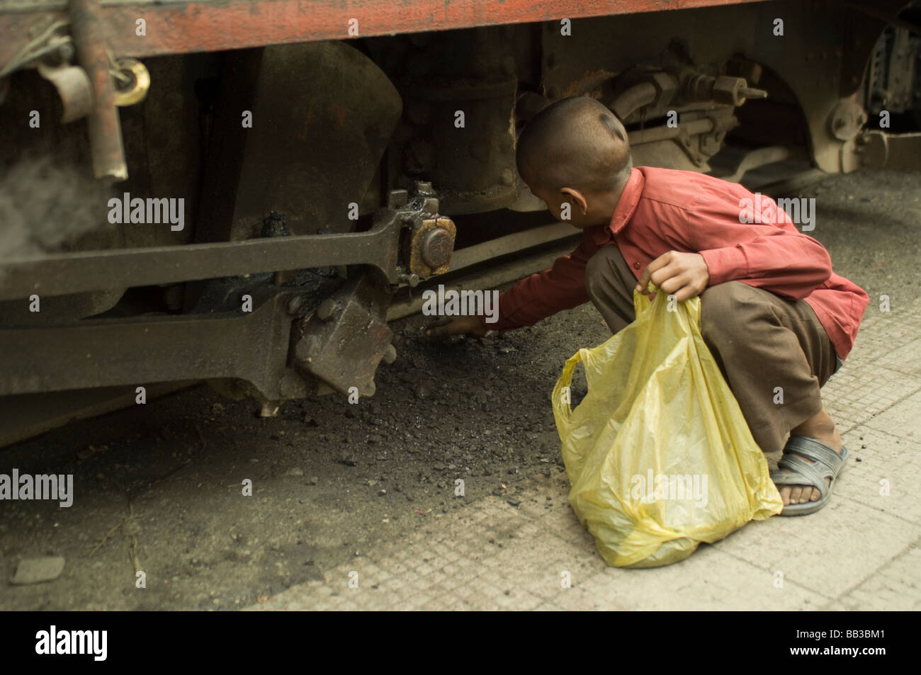 Young Boy taking burned coals from the Toy Train in Darjeeling India for use at home Stock Photo