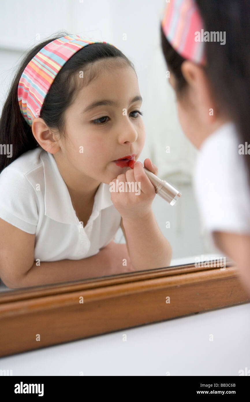 Little girl putting lipstick on Stock Photo