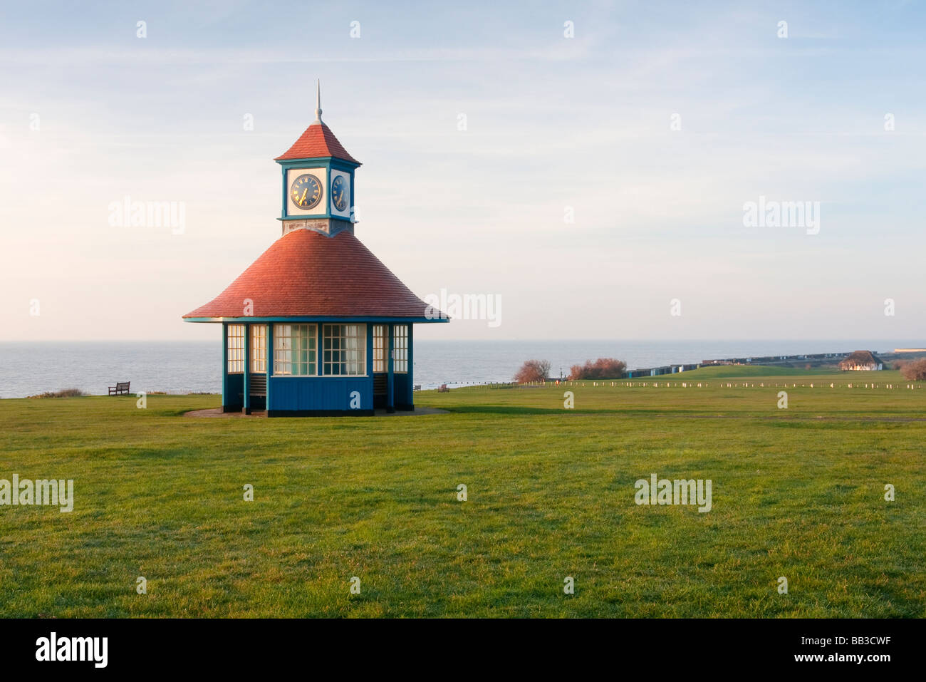 Rain / Weather shelter and clock down shortly after sunrise on the Essex coast at Frinton-on-sea Stock Photo