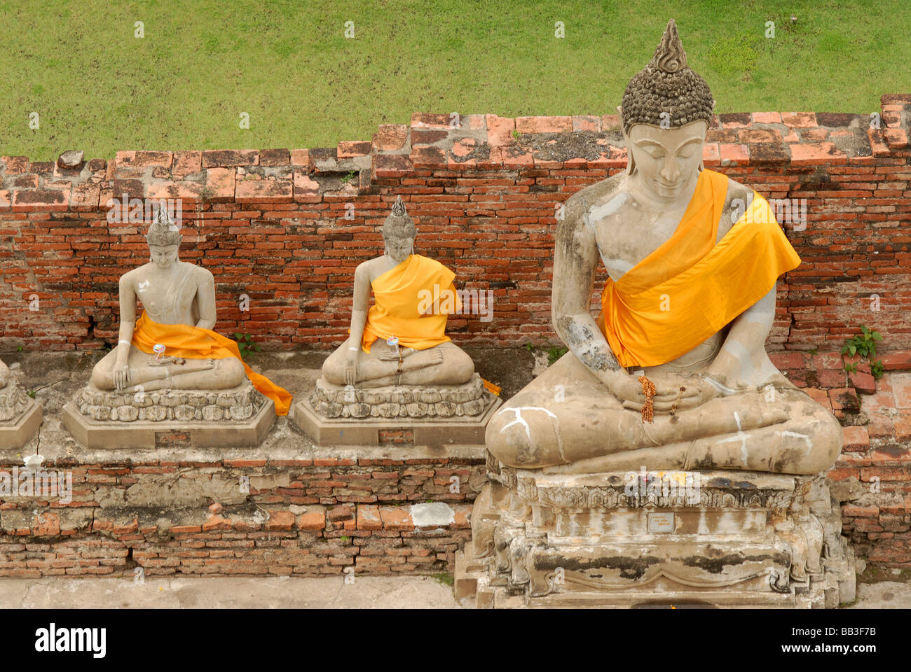 THAILAND, Ayutthaya. Statues of sitting buddhas wearing orange golden clothes around the chest, meditating at Ayutthaya Stock Photo