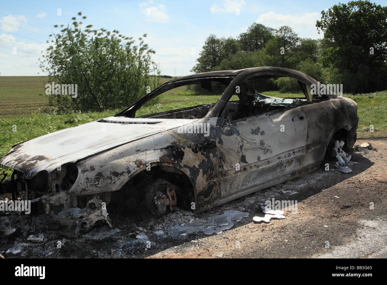 A burnt out shell of a Mercedes Benz Coupe left in rural farmland Stock Photo