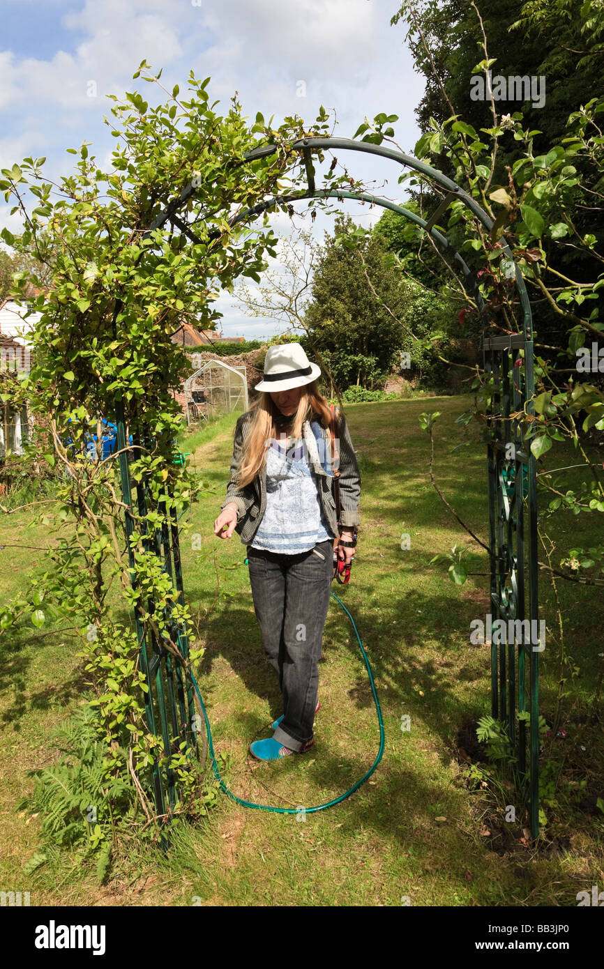 Woman Gardener Points To A Plant On A Rose Arch In A Kent Cottage Stock Photo Alamy