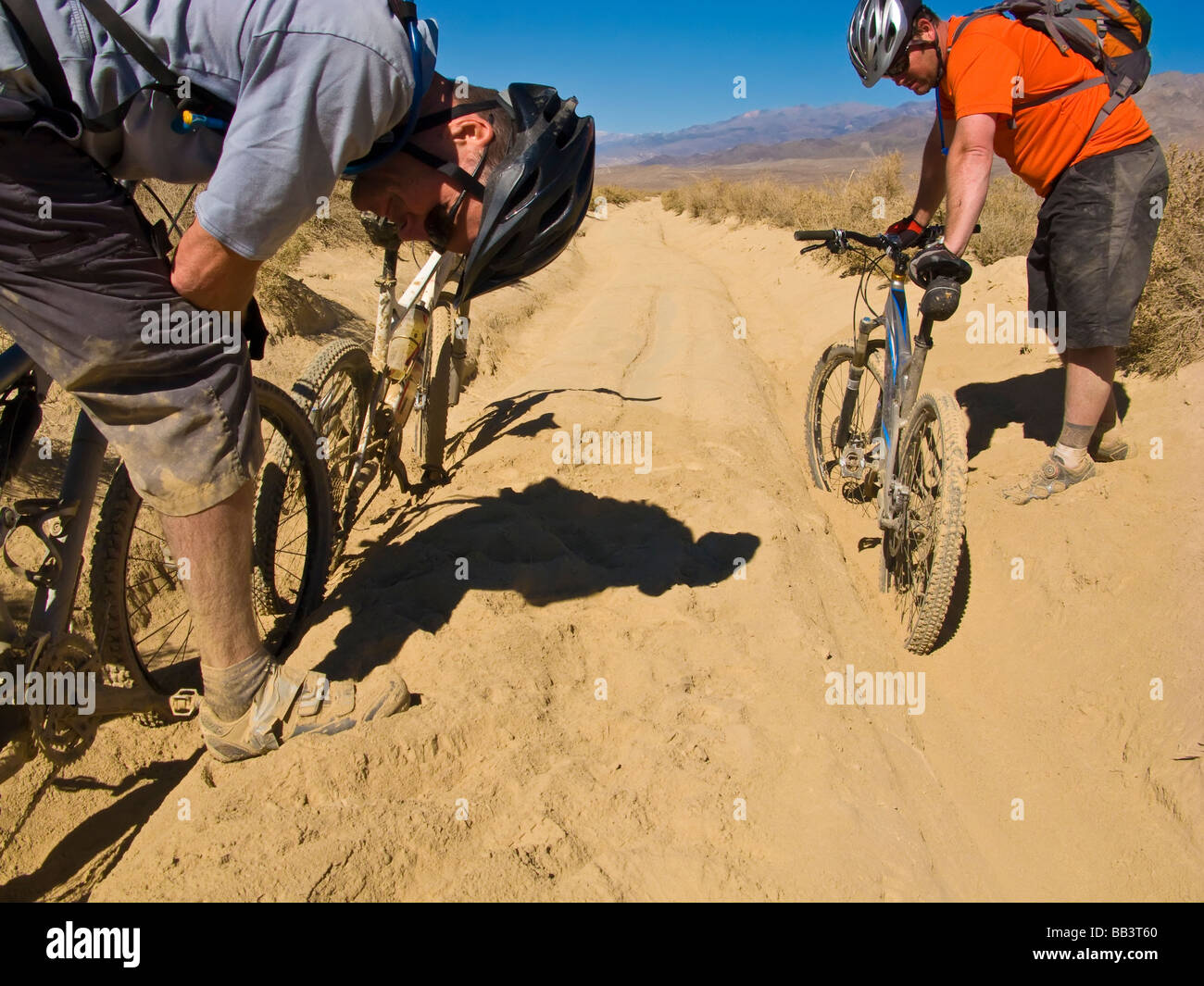 Mountain bikers stuck in deep sand on a remote dirt road Stock Photo