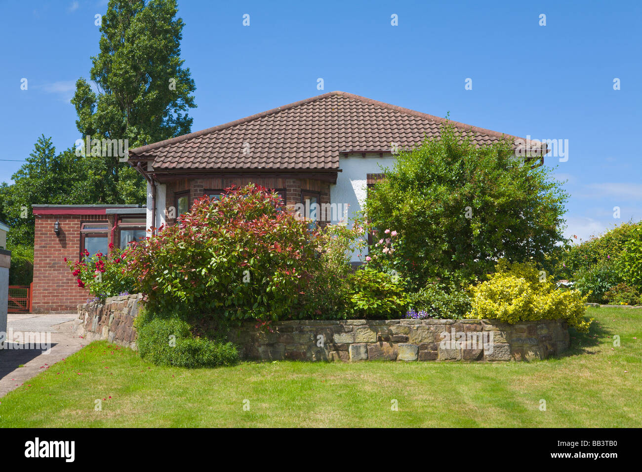 Terraced border of shrubs in garden and bungalow Stock Photo